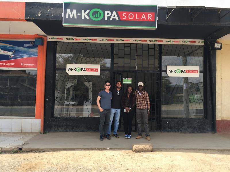 group of four people standing outside M-KOPA Solar store